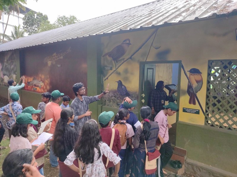 Pathanamthitta birdwatchers group looking at birds paintings on a wall